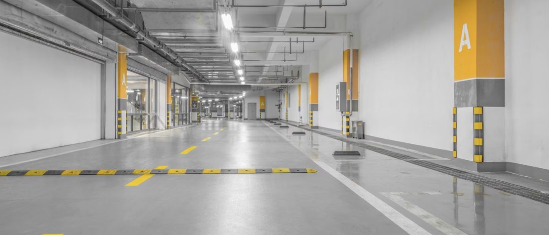 Nave industrial con piso pulido, líneas amarillas de delimitación y alumbrado lineal