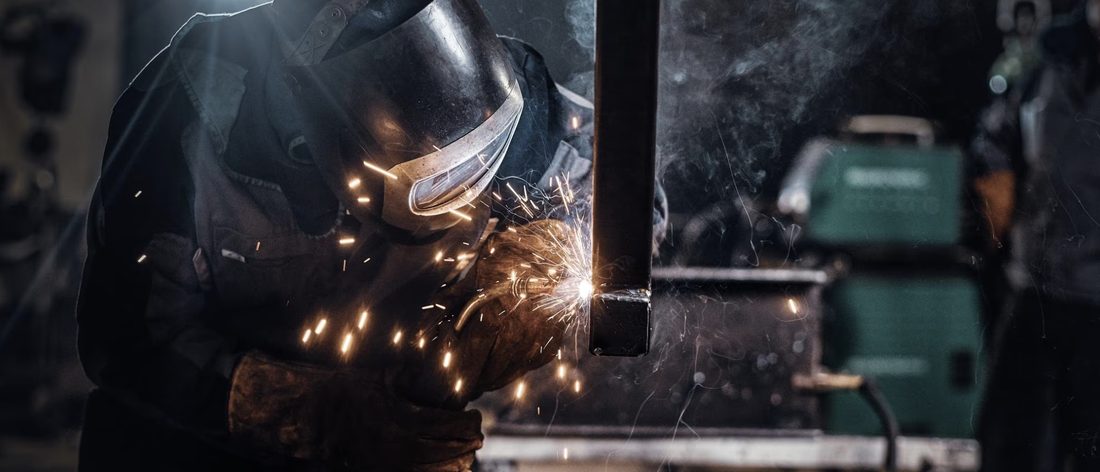 Soldador con careta trabajando una estructura metálica entre chispas