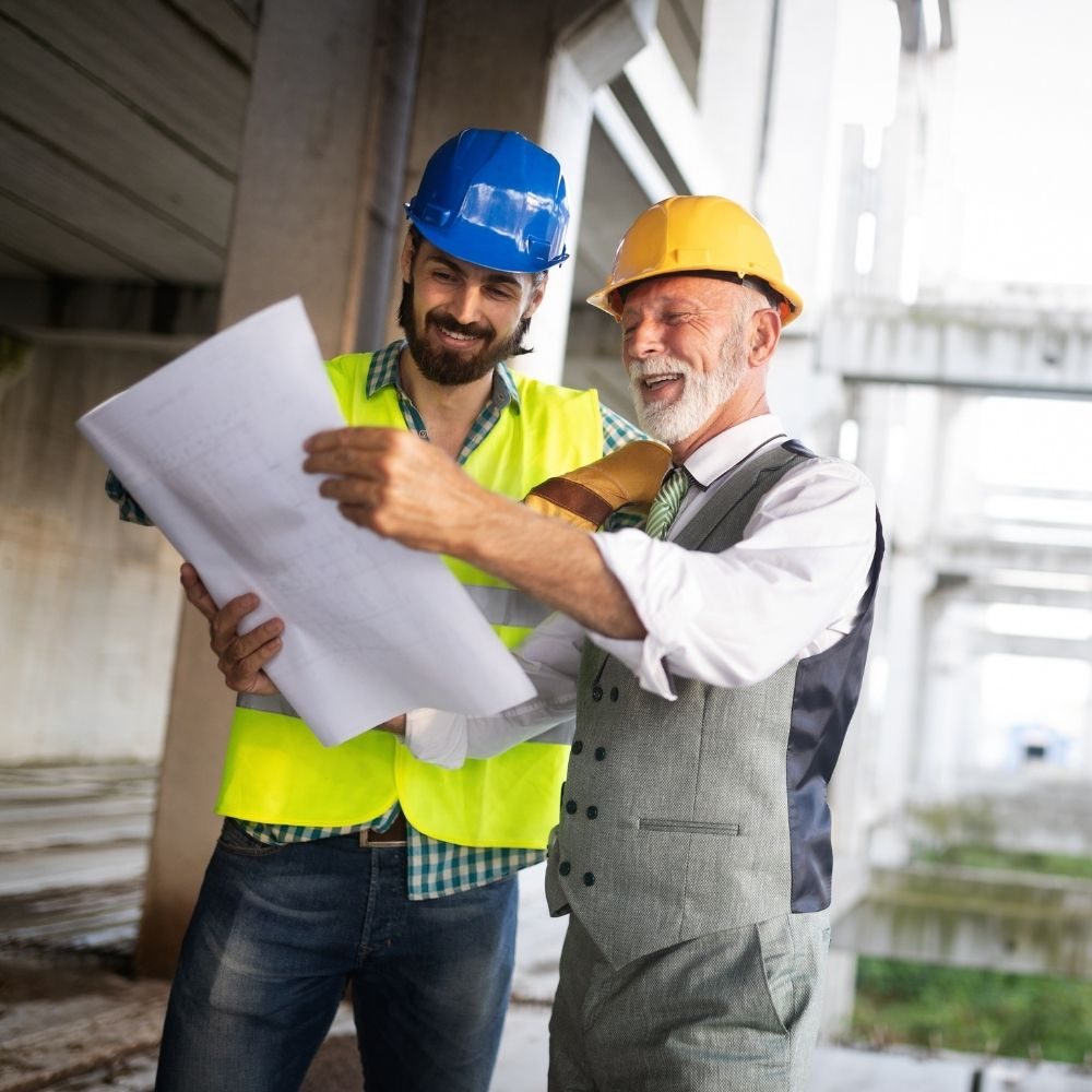 Ingenieros con casco revisando planos en una obra